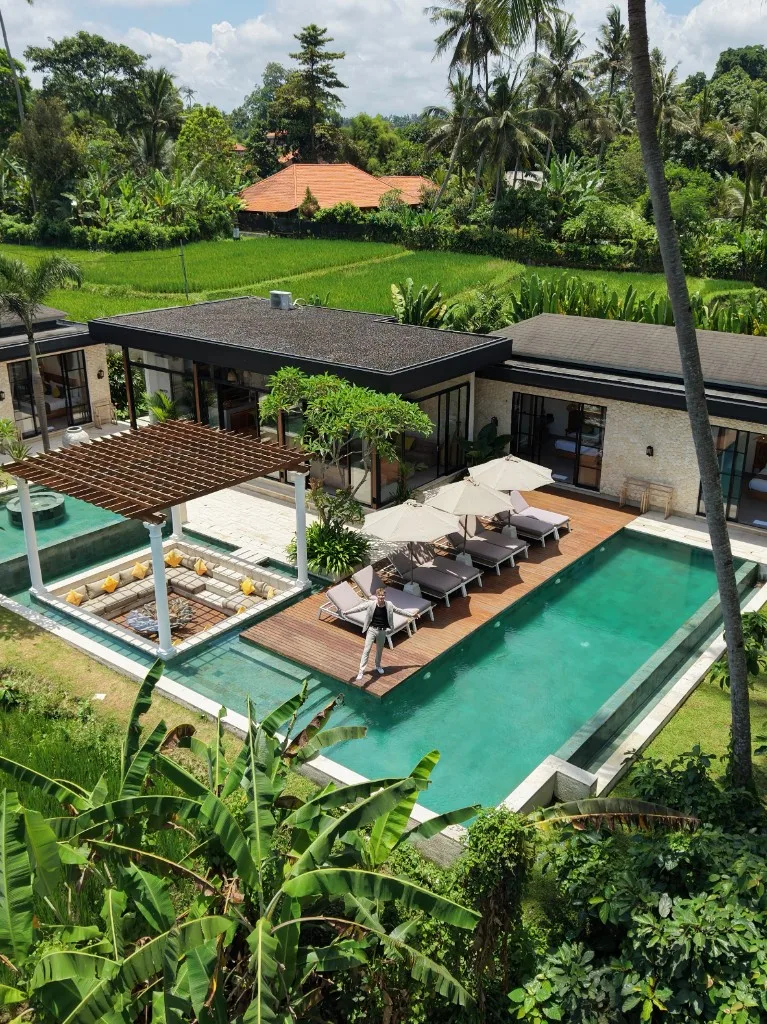 Aerial view of a villa pool, deck, and tropical grounds