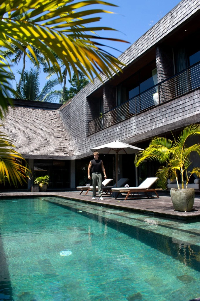 Lukas by a pool at a dark wood tropical villa with palm trees